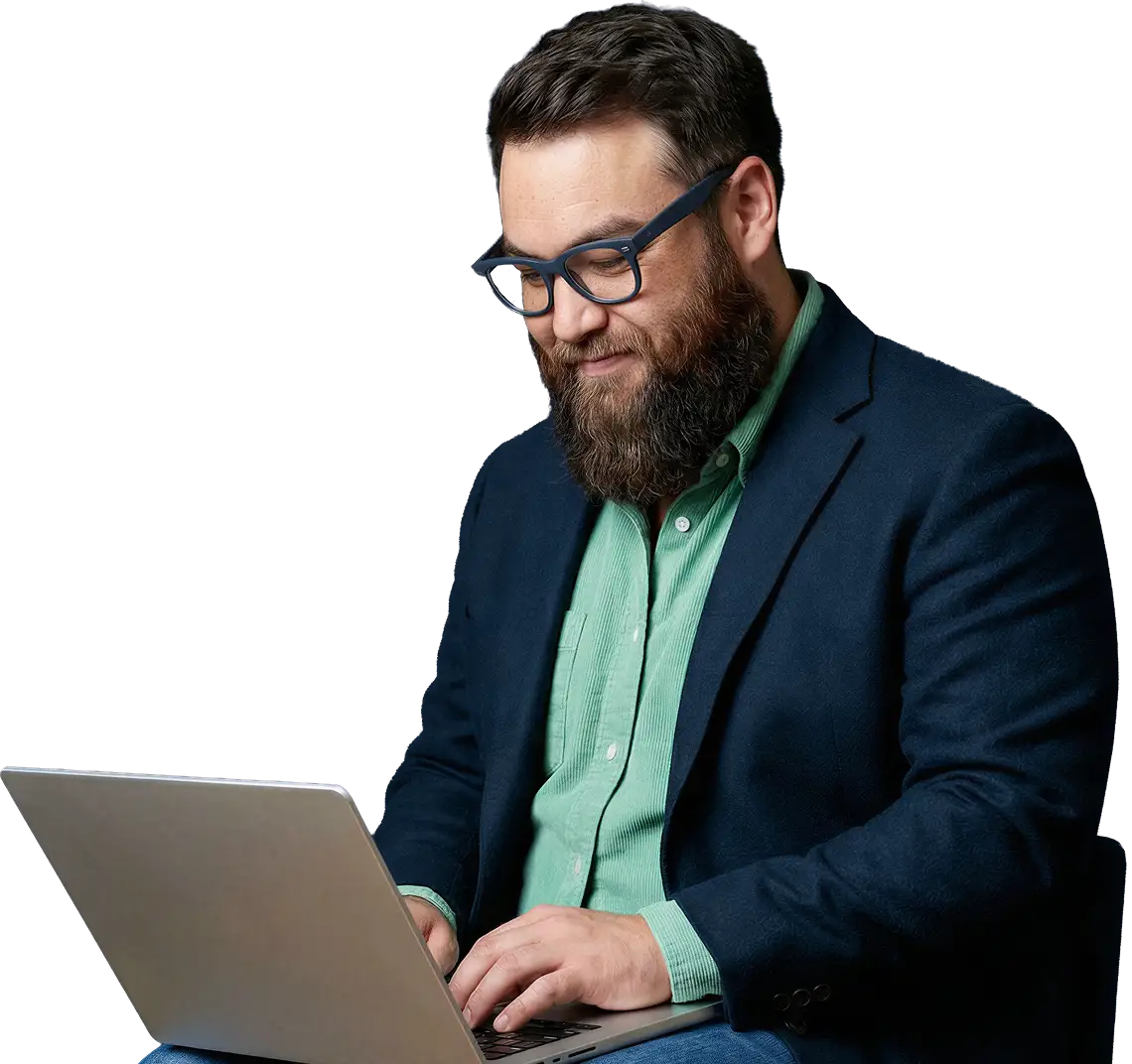 Bearded man wearing glasses and blazer working on a laptop