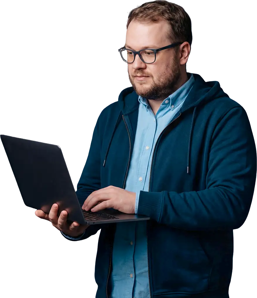 usecases-empower-hero-p1 A professional man with glasses and a beard working on a laptop, wearing a navy hoodie